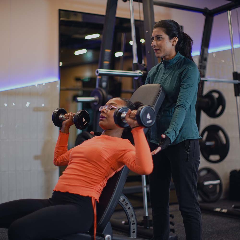 women lifting weight with another woman spotting her